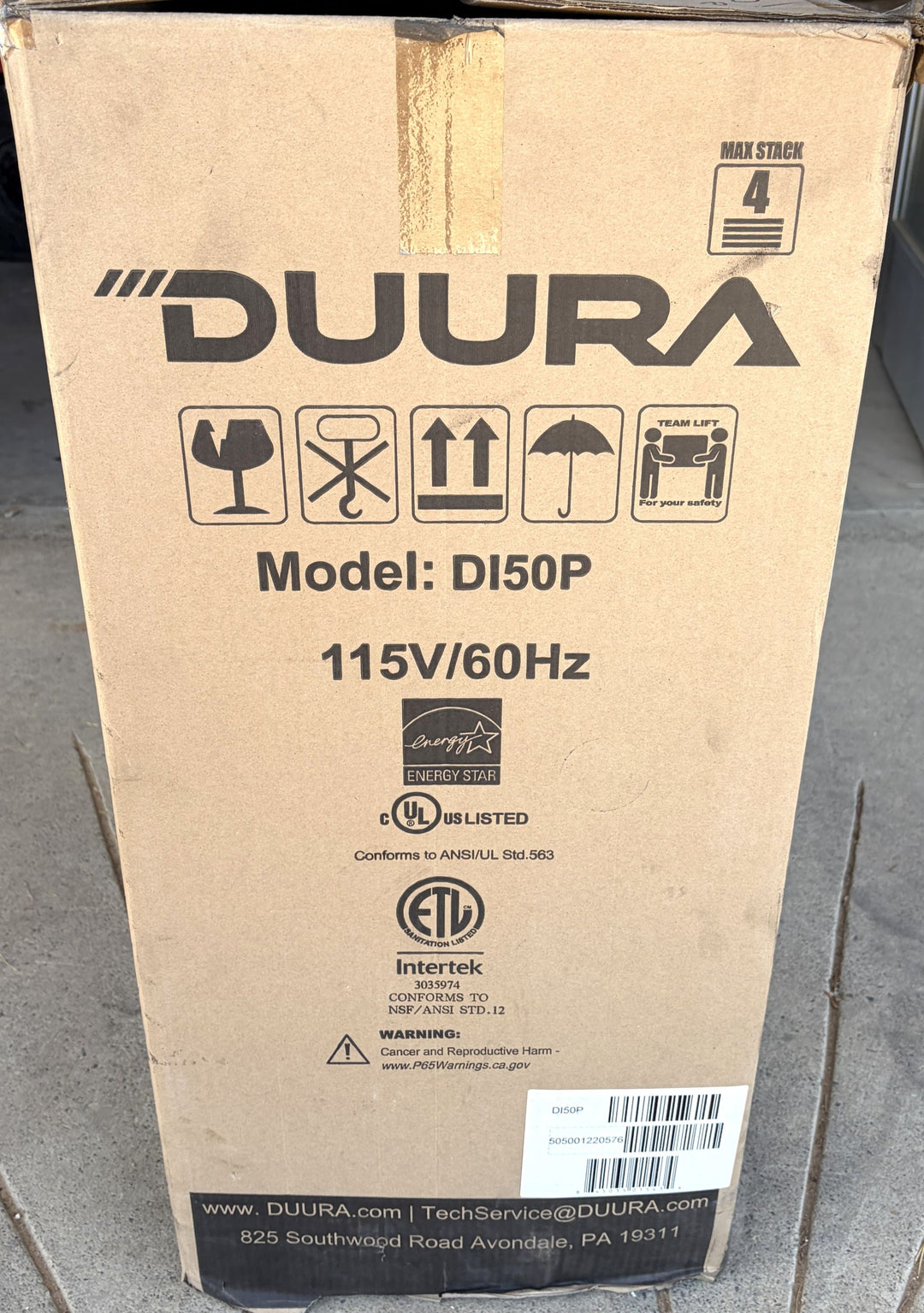 Cardboard packaging box for a Duura built-in ice maker model DI50P featuring energy efficiency and safety certification labels, handling icons, and company contact information.