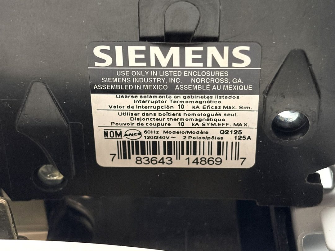 Close-up of a Siemens electrical panel label showing certification marks, voltage rating of 120/240V, 60Hz frequency, and assembly details with a clear barcode on a black panel.