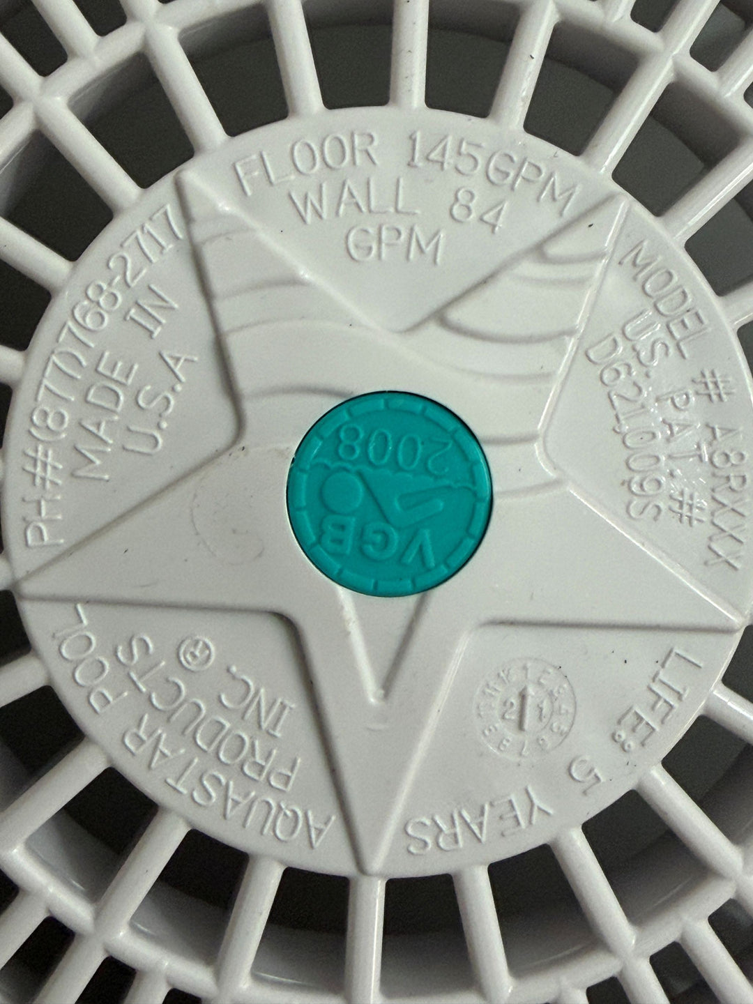 Close-up of a white AquaStar pool suction outlet drain cover featuring embossed specifications, a star-shaped design, and a blue VGB 2008 compliance seal in the center.