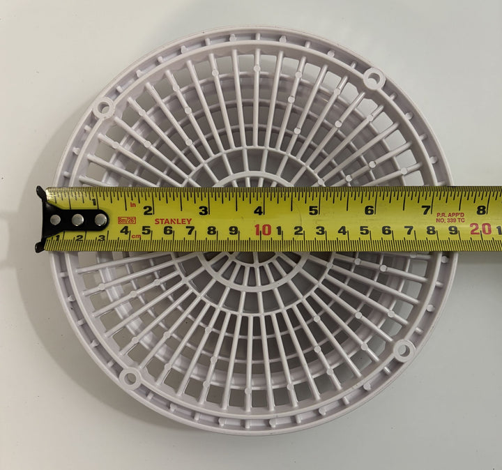 Circular white plastic pool suction outlet drain cover from AquaStar with a yellow measuring tape across it showing dimensions for scale.