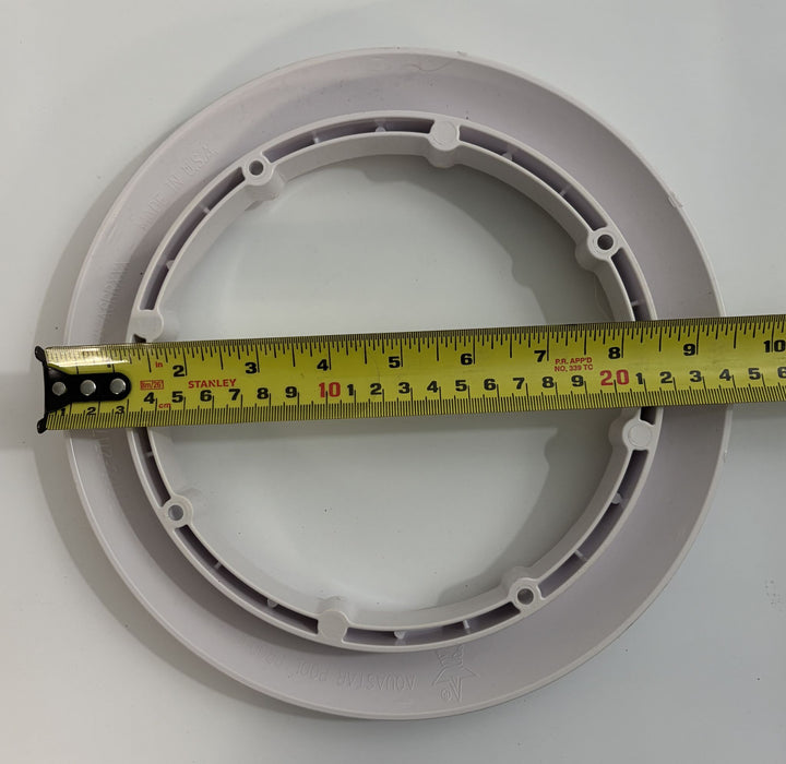 A white round pool drain cover with a built-in mounting ring, shown with a measuring tape across its diameter, featuring AquaStar branding.