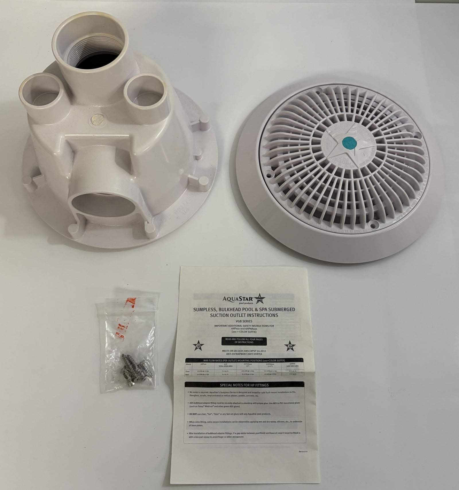 AquaStar white pool suction outlet drain cover set displayed on a white surface, including the drain body, round vented cover, hardware screws in a plastic bag, and an instruction sheet.