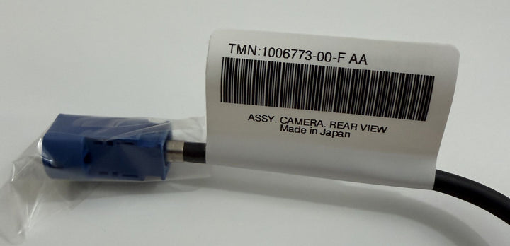 Close-up of a Tesla OEM rear view camera harness assembly with a blue connector and barcode label indicating part number and origin.