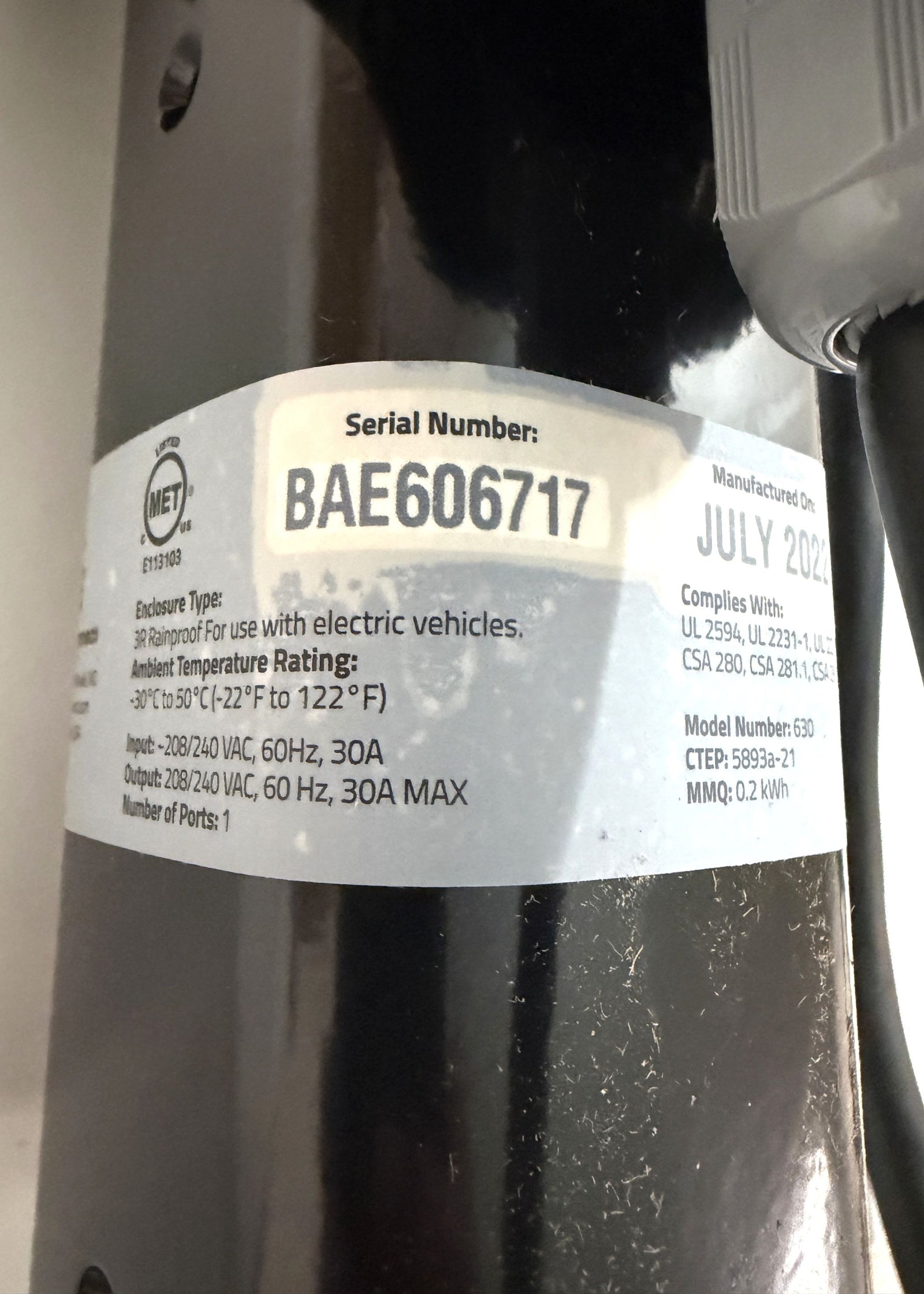 Close-up of a label on a black SemaConnect commercial EV charger showing serial number, manufacturing date, electrical ratings, and compliance information.
