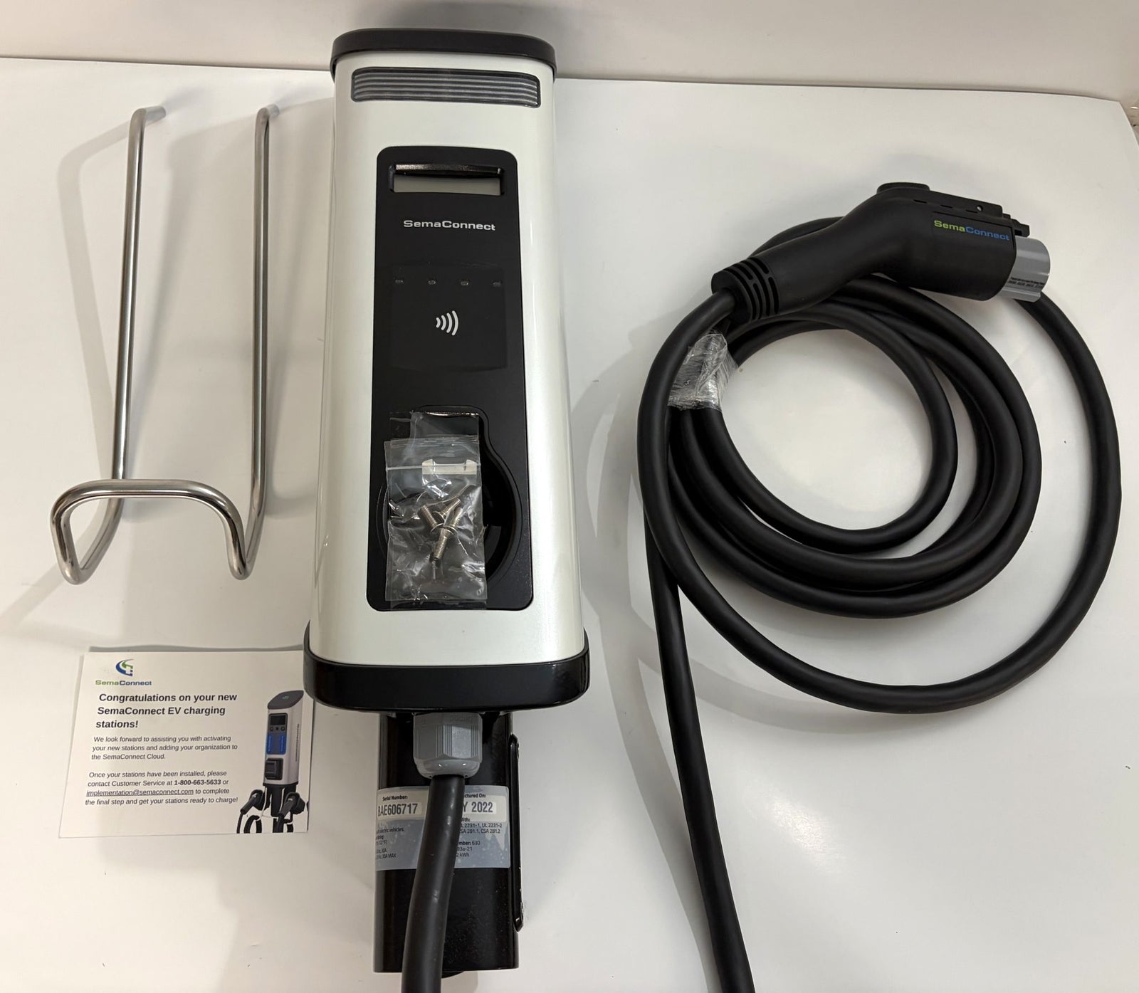 SemaConnect branded commercial-grade Level 2 electric vehicle charger with attached cable, metal mounting bracket, screws, and instruction card on a white surface.