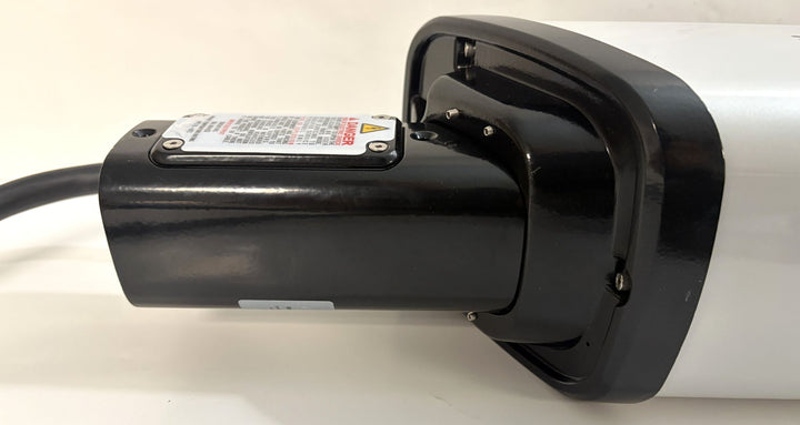 Close-up of a black and white commercial-grade electric vehicle charging connector from SemaConnect, showing durable housing and cable attachment point.