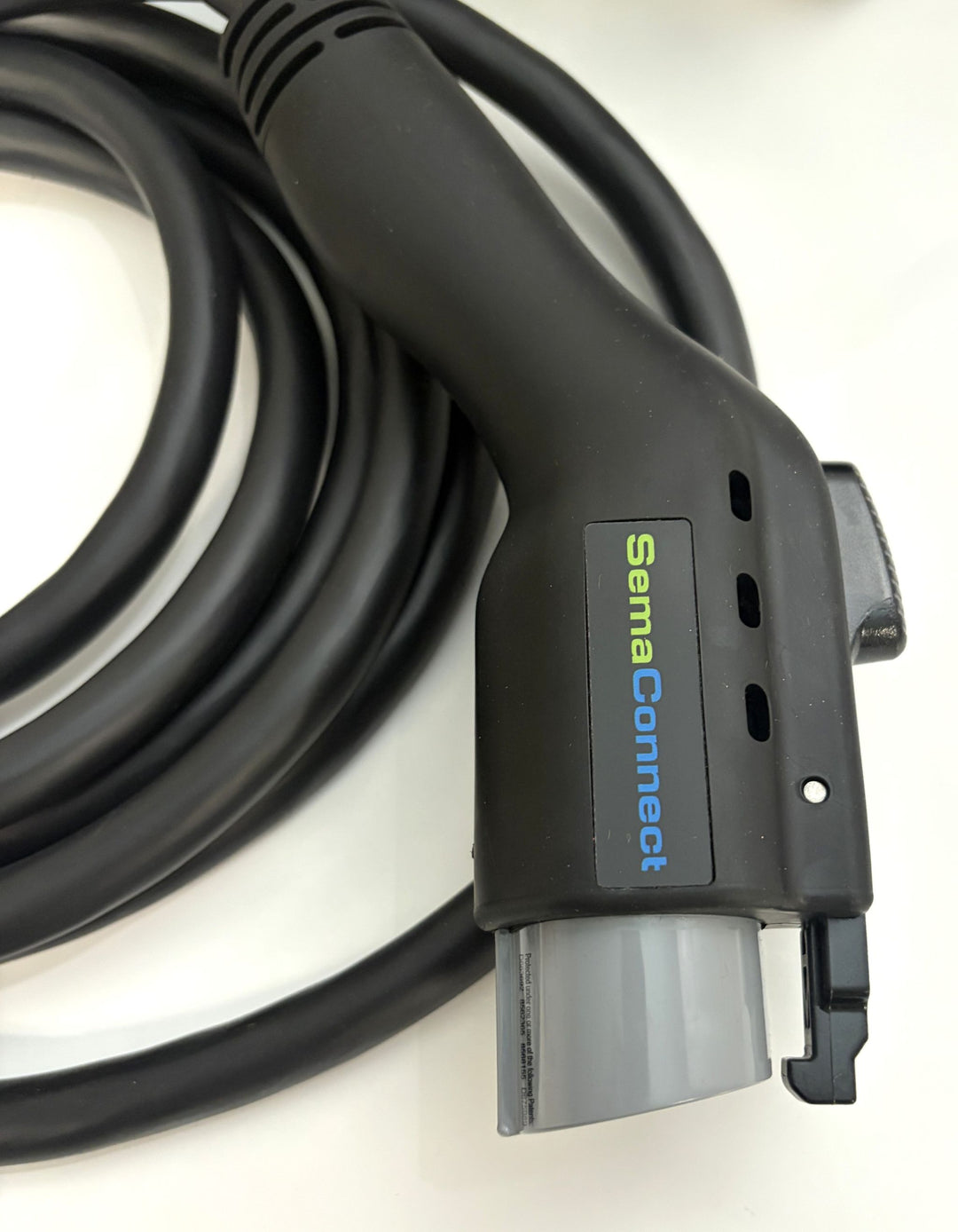 Close-up of a black SemaConnect branded electric vehicle charging connector with a coiled cable, designed for commercial Level 2 EV charging stations.