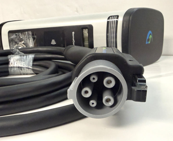 Close-up of a SemaConnect branded commercial-grade Level 2 electric vehicle charging connector with attached cable, shown coiled on a light surface.