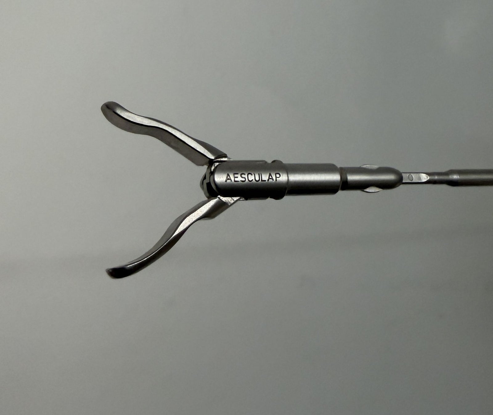 Close-up of a stainless steel laparoscopic grasping forceps insert with wave-shaped jaws, branded by Aesculap, designed for minimally invasive surgical procedures.