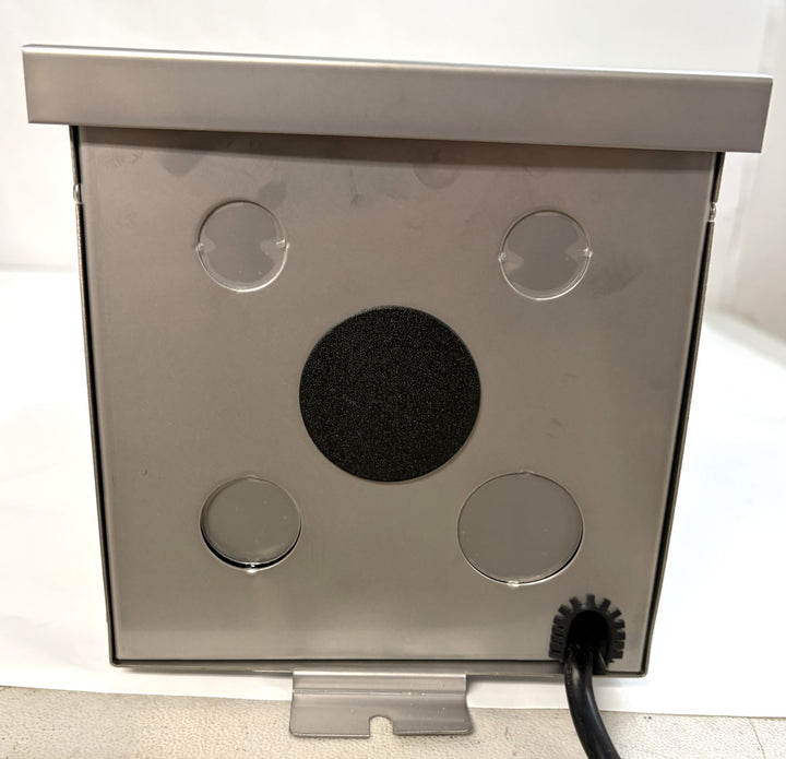 Stainless steel outdoor transformer unit by Dauer with circular ventilation openings and a black foam pads, designed for landscape electrical applications.