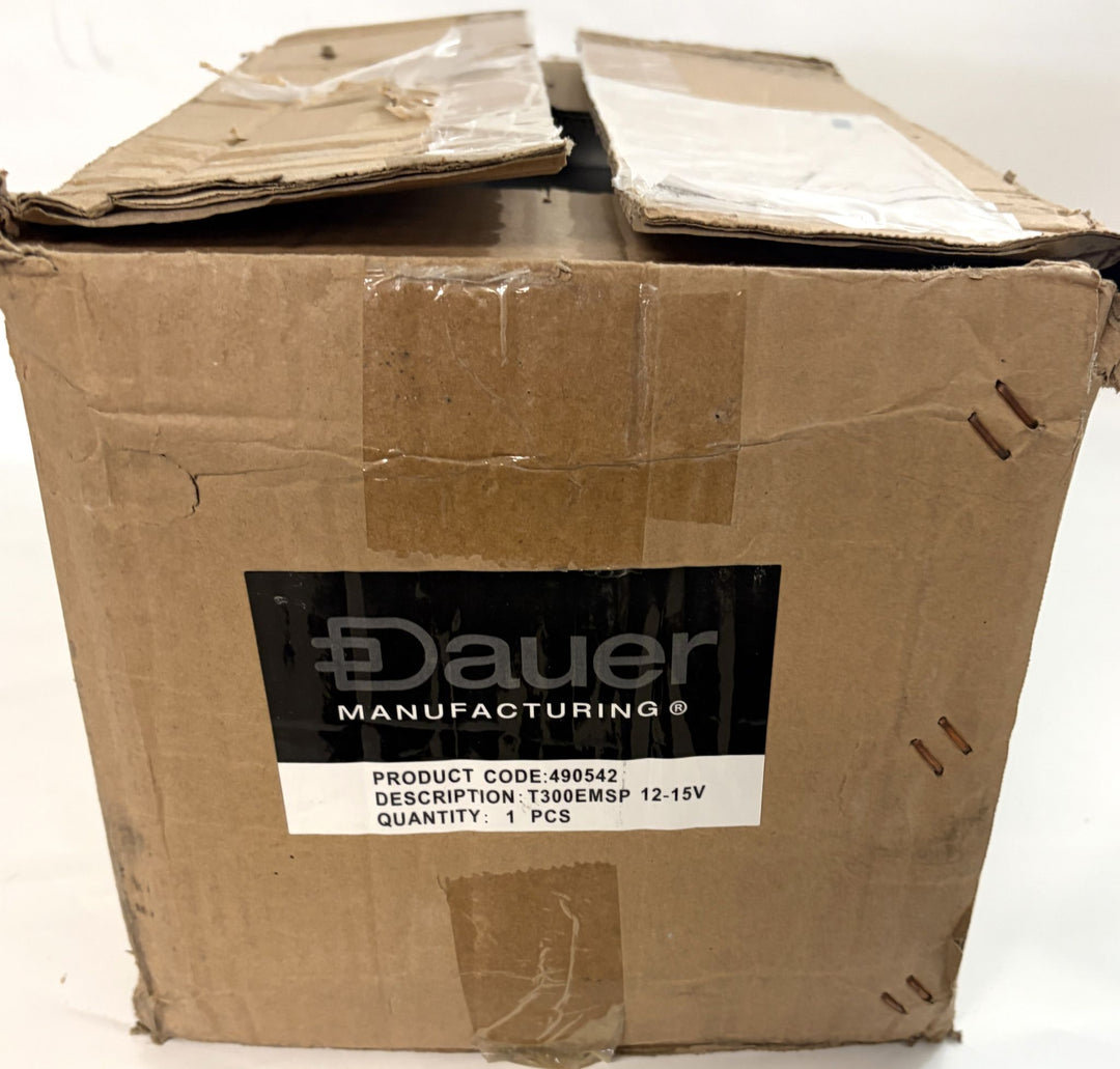 Worn cardboard shipping box with a taped flap, featuring a black and white Dauer Manufacturing label indicating product code and voltage details for an electrical component.
