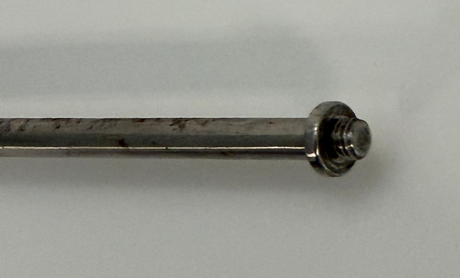 Close-up of a metal threaded rod with a round flange end, part of a precision instrument from Depuy AcroMed, suitable for medical or industrial use.