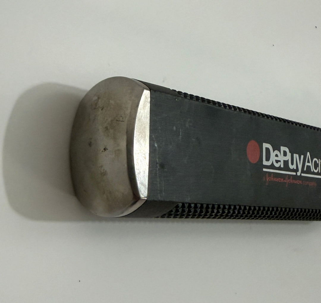 Close-up of a medical instrument handle with a metallic rounded end and black textured grip, featuring the brand name Depuy AcroMed on the side.