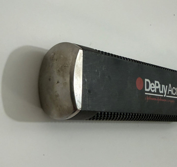 Close-up of a medical instrument handle with a metallic rounded end and black textured grip, featuring the brand name Depuy AcroMed on the side.