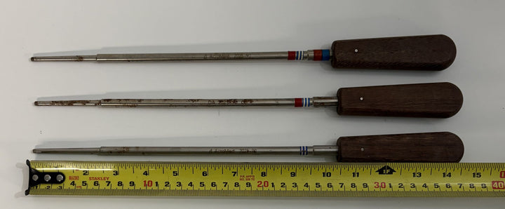 Set of three Depuy AcroMed spinal pedicle probe instruments with wooden handles and metal shafts, shown alongside a measuring tape for scale.