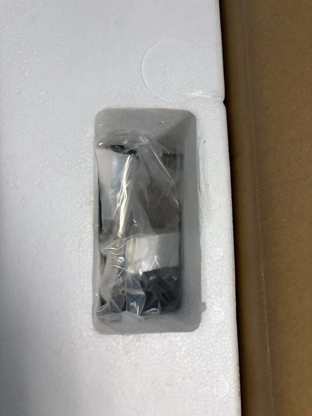 Dremel scroll saw component wrapped in protective plastic and nestled securely within white foam packaging inside a cardboard box, ready for safe transport.