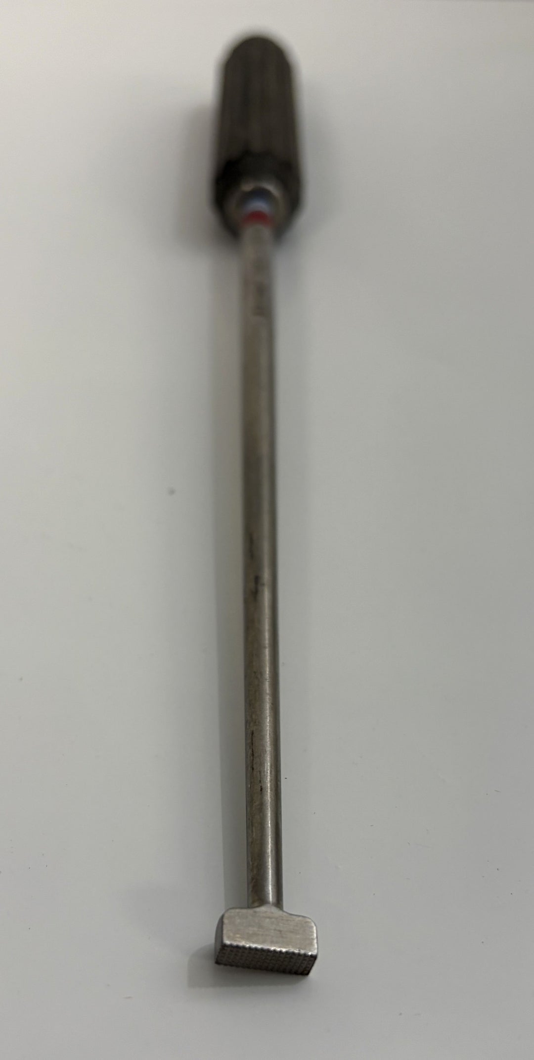 AcroMed bone graft impactor featuring a textured metal tip and grooved black handle, designed for precision use in spinal surgical procedures.