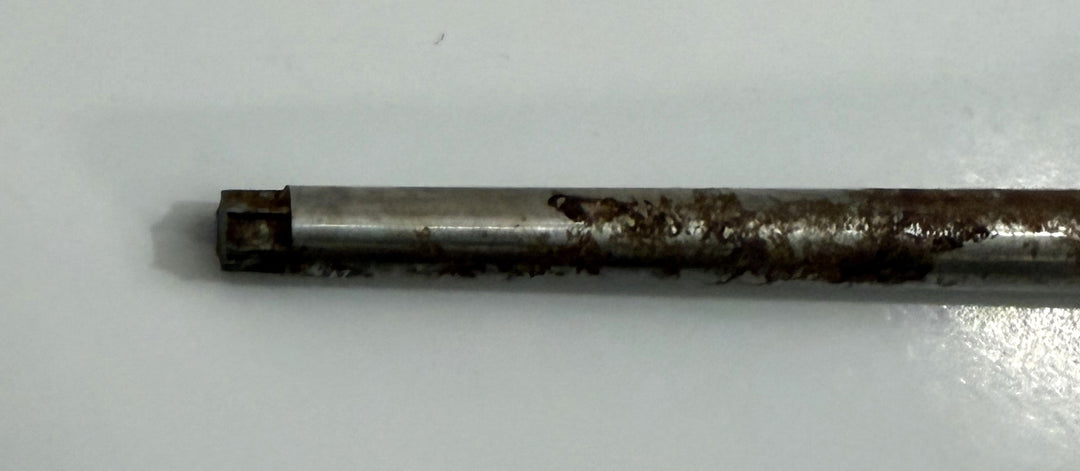 Close-up of a metallic spinal pedicle probe instrument from Depuy AcroMed, showing wear and surface rust on the cylindrical shaft used in medical procedures.