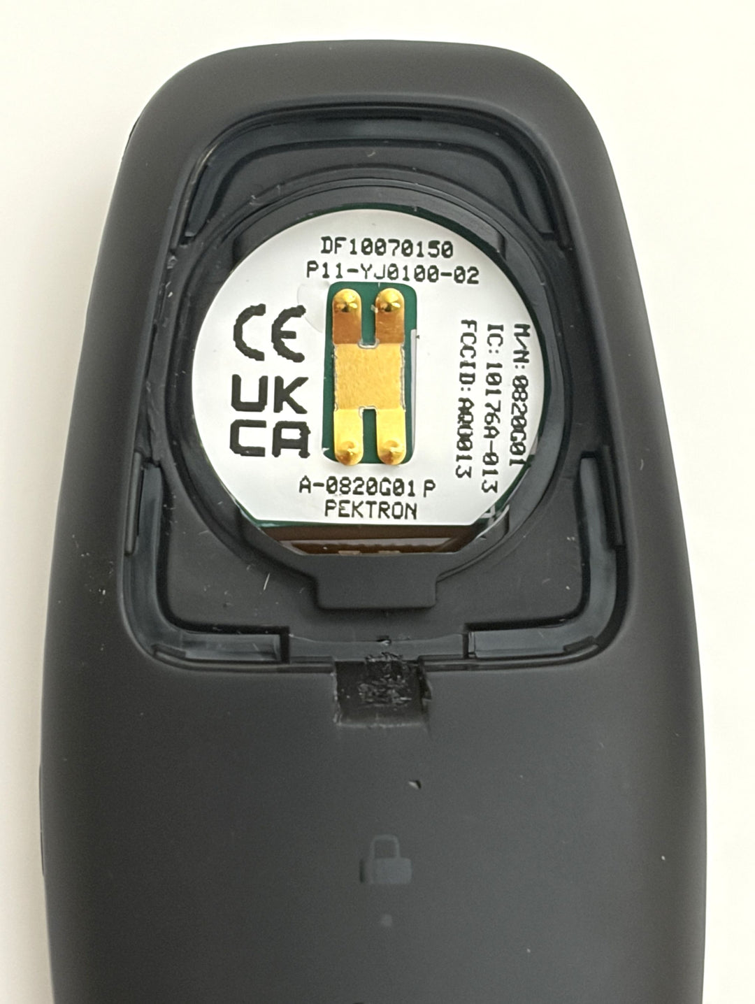 Close-up of the interior electronic component of a Lucid smart key fob, showing a round circuit board with gold contacts and regulatory markings inside a black plastic casing.