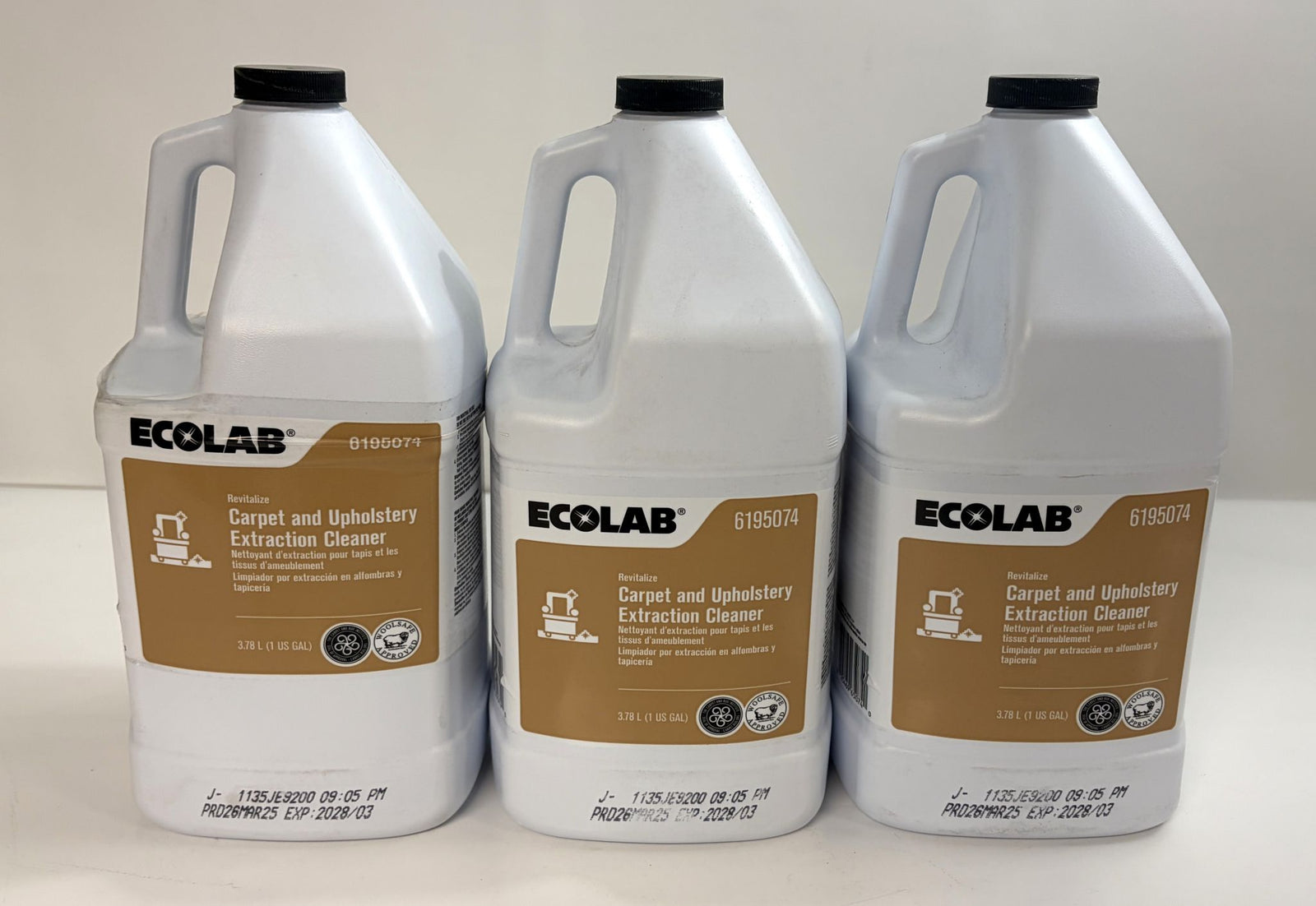 Three white gallon containers of Ecolab Revitalize carpet and upholstery extraction cleaner with brown and white labels, arranged side by side on a light background.