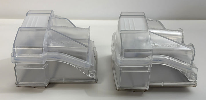 Two clear plastic replacement water chambers designed for Resmed humidifier devices, shown side by side on a plain surface.