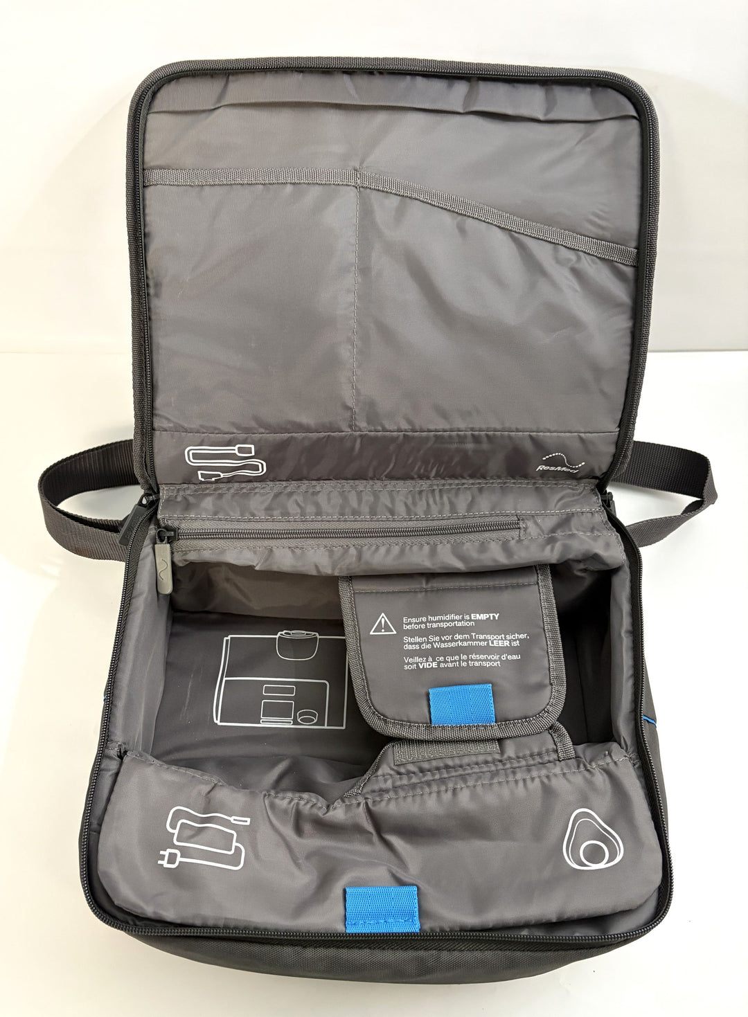 Open charcoal gray travel bag designed for Resmed AirSense 10 CPAP device, featuring multiple internal compartments and labeled storage pockets for medical accessories.