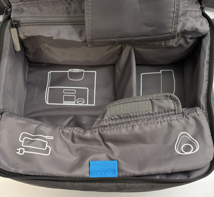 Interior view of a charcoal gray Resmed travel bag designed with compartments and printed icons to organize CPAP machine components and accessories efficiently.