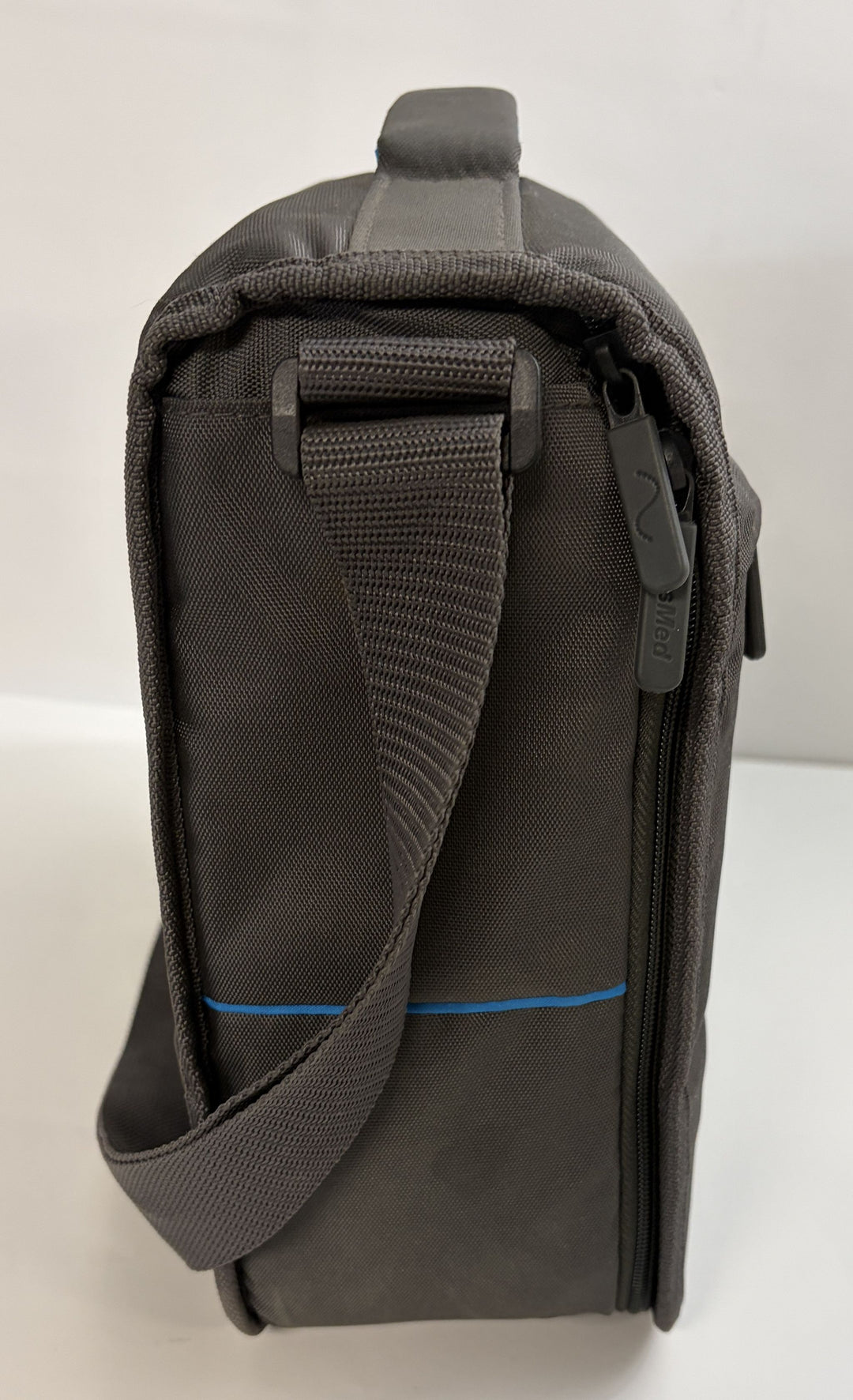 Side view of a charcoal gray Resmed travel bag featuring a durable woven strap and a zipper pull embossed with the brand name, designed for CPAP device portability.