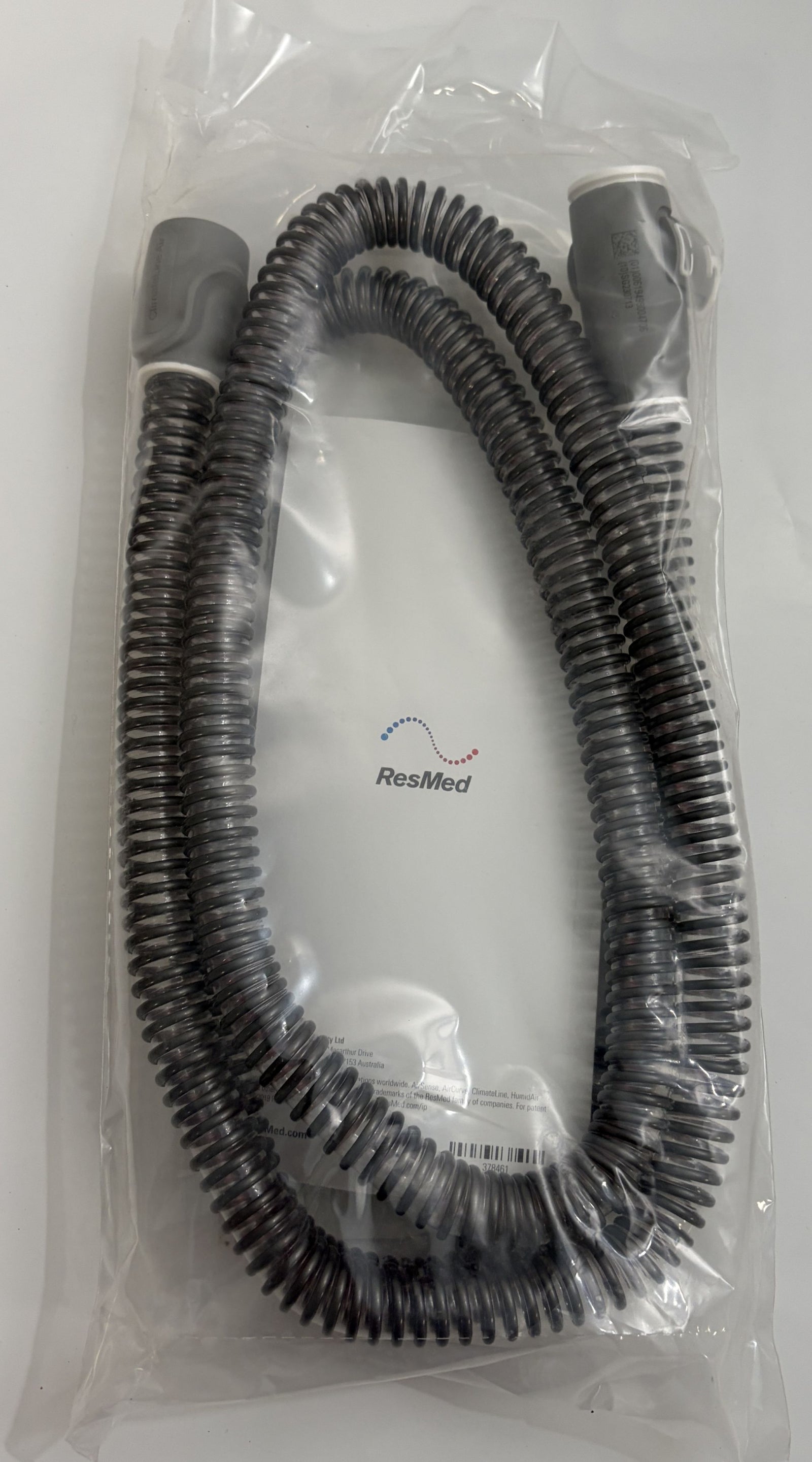 Coiled black heated breathing tube for CPAP machine by Resmed, sealed in clear plastic packaging with visible branding and product information.