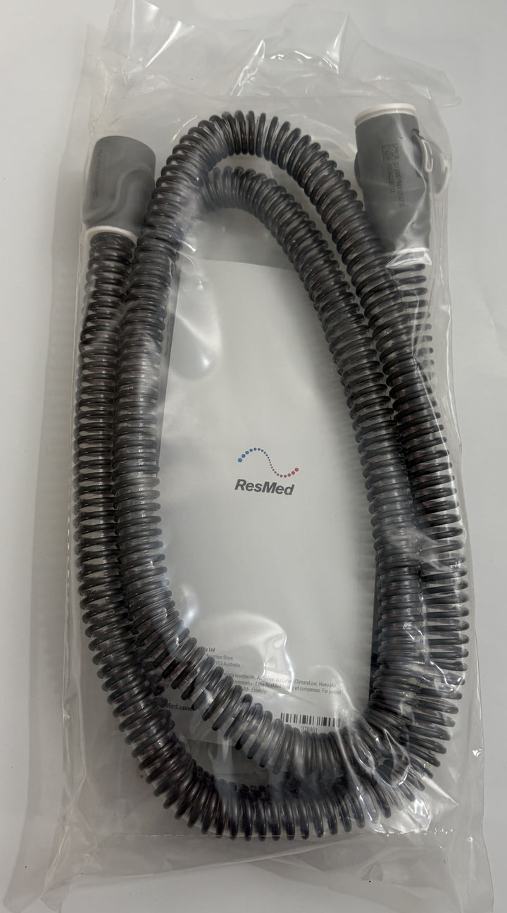 Coiled black heated breathing tube for CPAP machine by Resmed, sealed in clear plastic packaging with visible branding and product information.