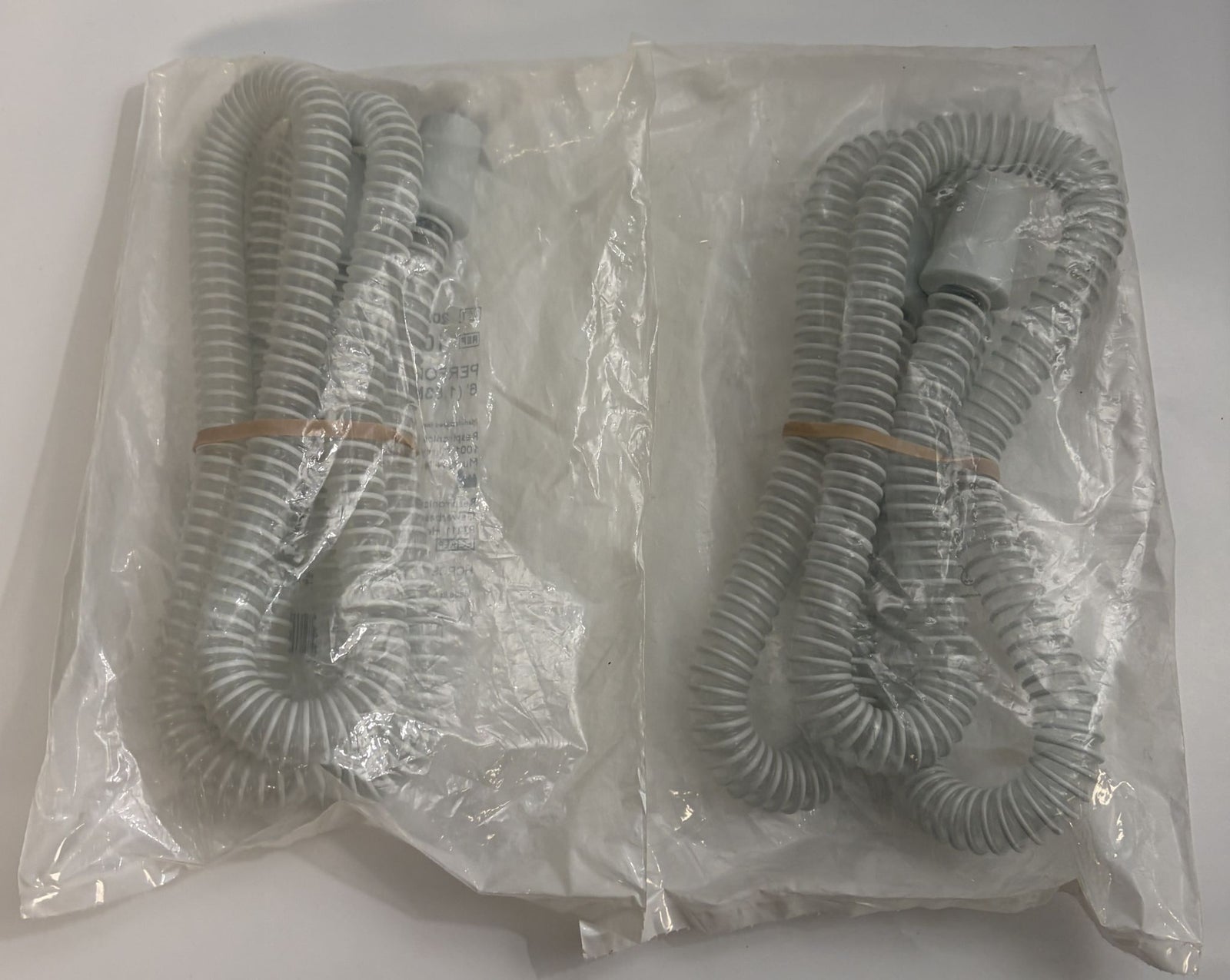 Pair of coiled gray Respironics CPAP tubing pieces in sealed clear plastic packaging, designed for medical respiratory therapy use.