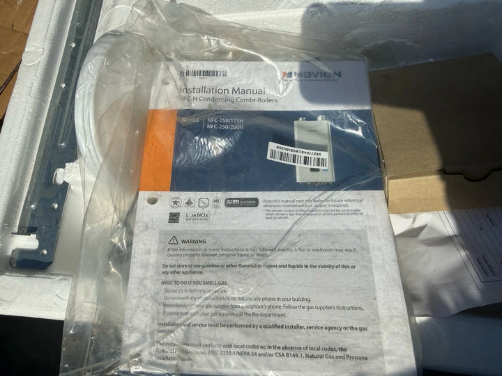 Navien installation manual for H Series condensing combi boilers, sealed in clear plastic packaging with a barcode label and safety instructions visible.
