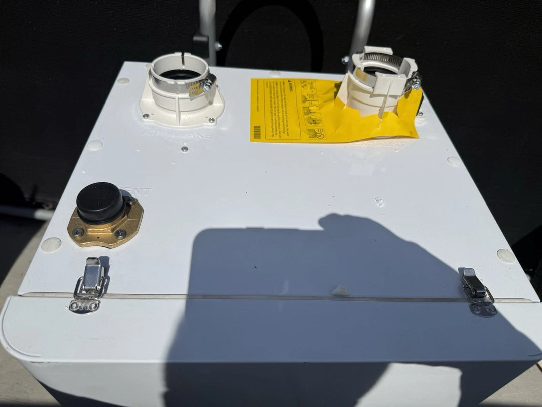 White electrical enclosure with circular cable connectors, black control knob, metal latches, and a yellow warning label on top against a dark background.