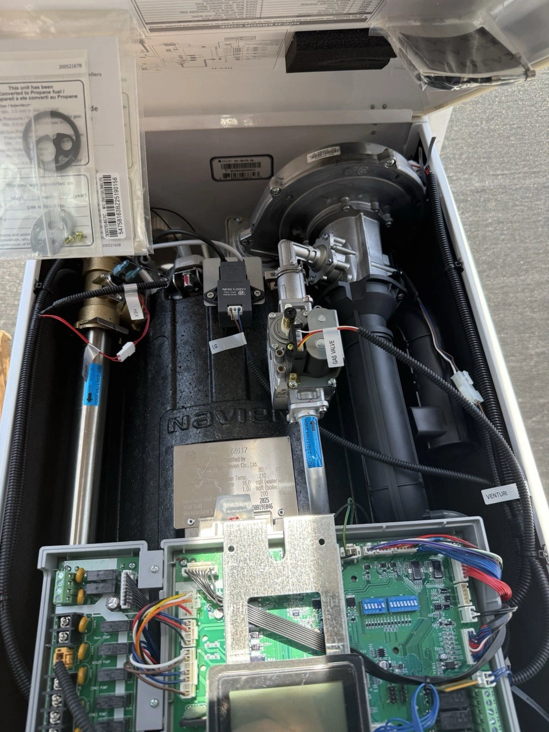 Open industrial equipment enclosure showing circuit boards, wiring, valves, tubing, and a large black motor assembly.