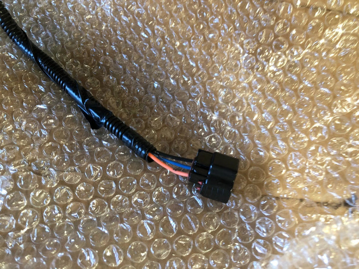 New Yamaha OEM J5A-H2590-10-00 wire harness assembly with black protective sheathing and electrical connector on bubble wrap