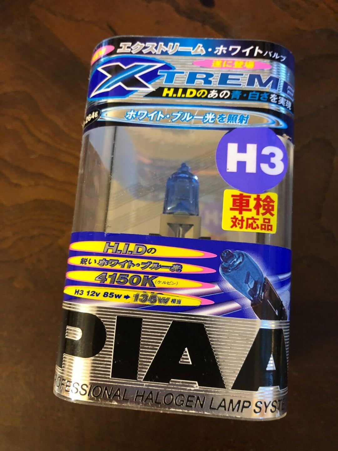 PIAA branded H3 halogen fog light bulb with blue tint, packaged in clear plastic with Japanese text, highlighting 4150K bright white and blue light output for automotive use.